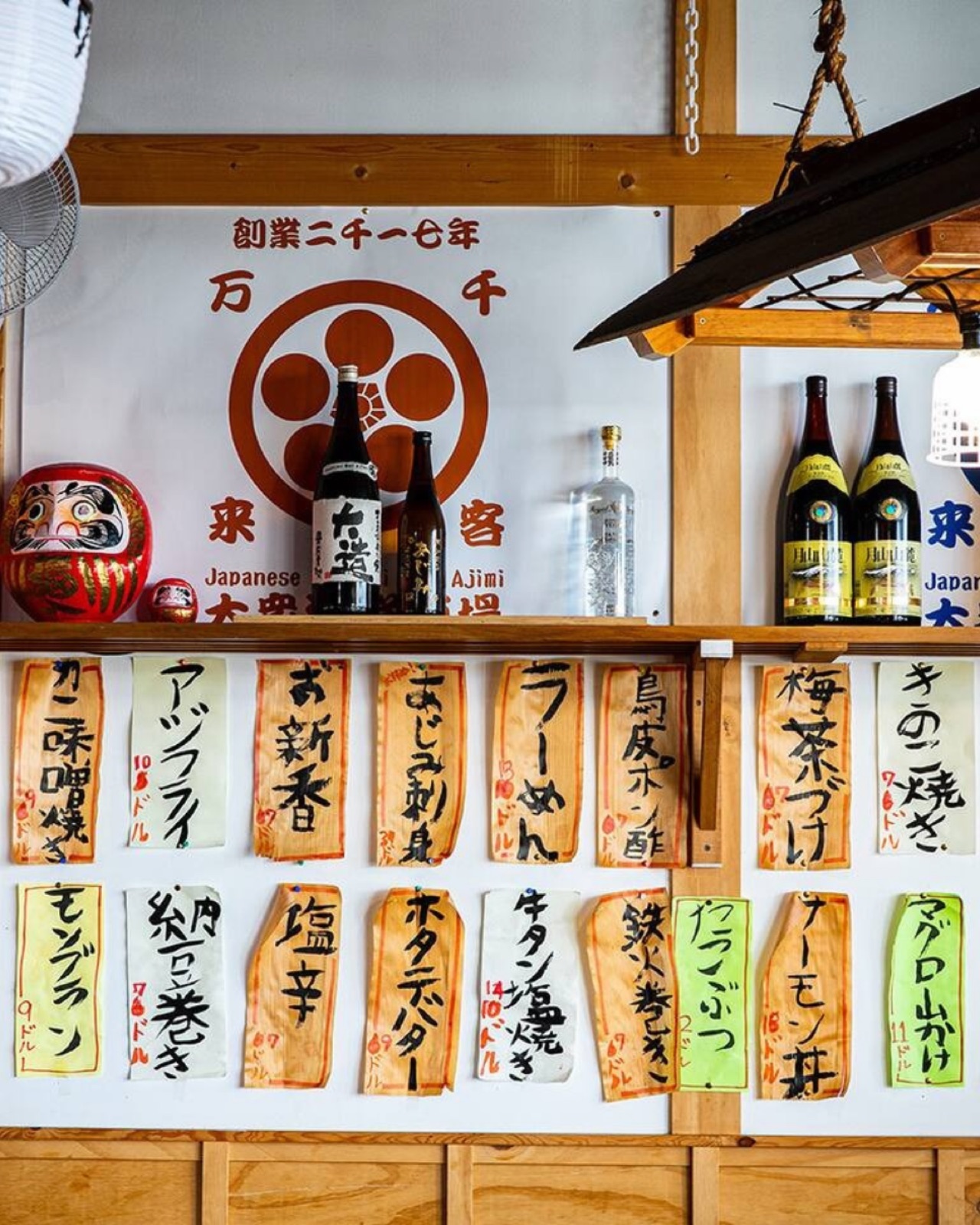 Japanese Sashimi Bar AJIMI interior with the restaurant's crest and handwritten menu boards